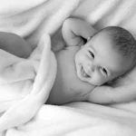 Bild mit einem lachenden Baby auf einer Decke