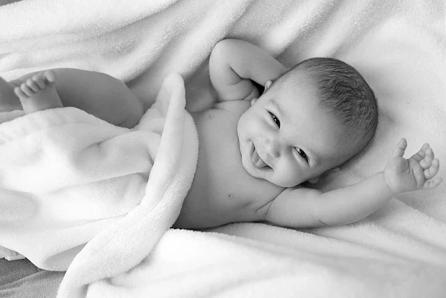 bed-1839564_640 Bild mit einem lachenden Baby auf einer Decke